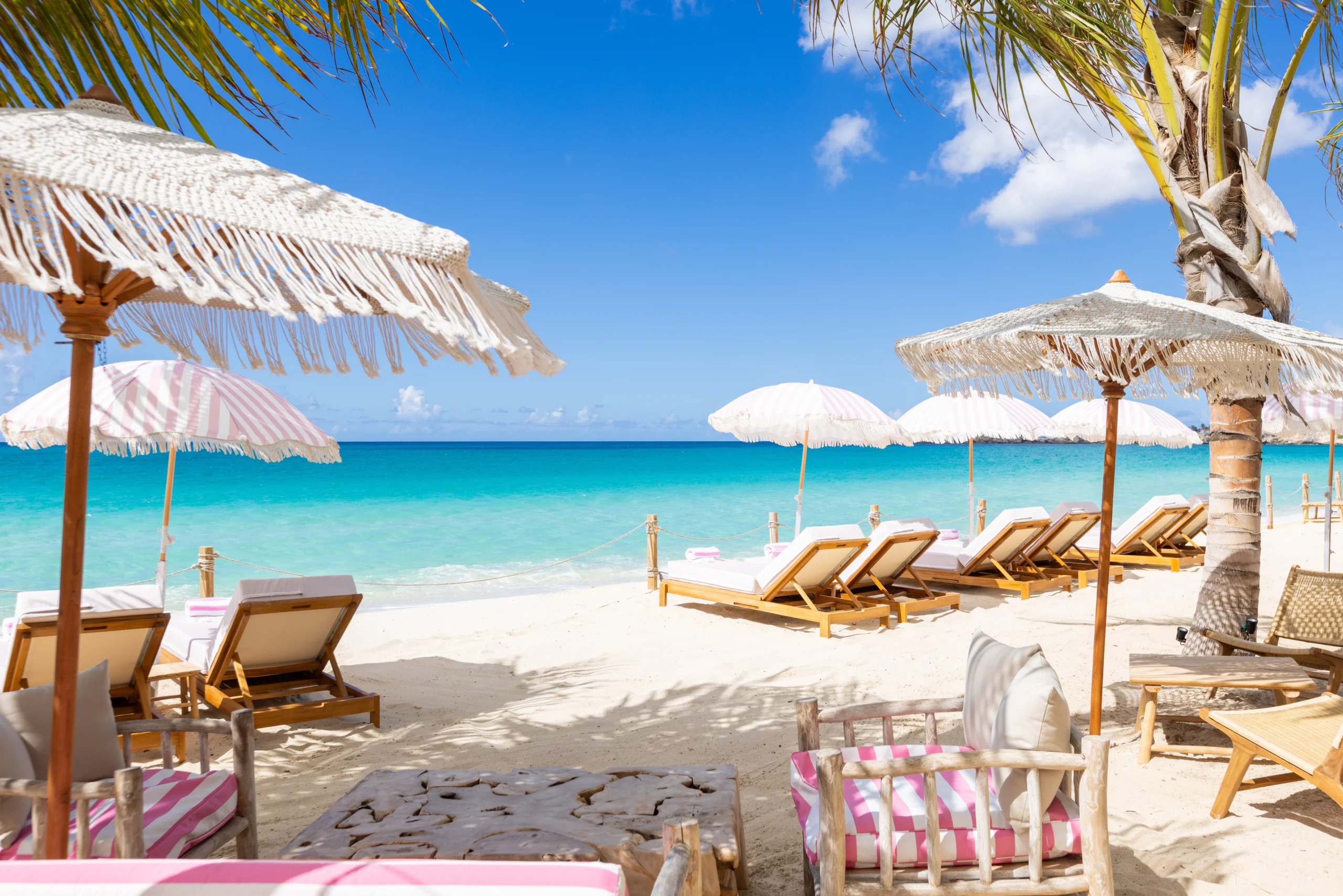 White fringed parasols and beach loungers overlooking the turquoise Caribbean at Babacool Beachclub